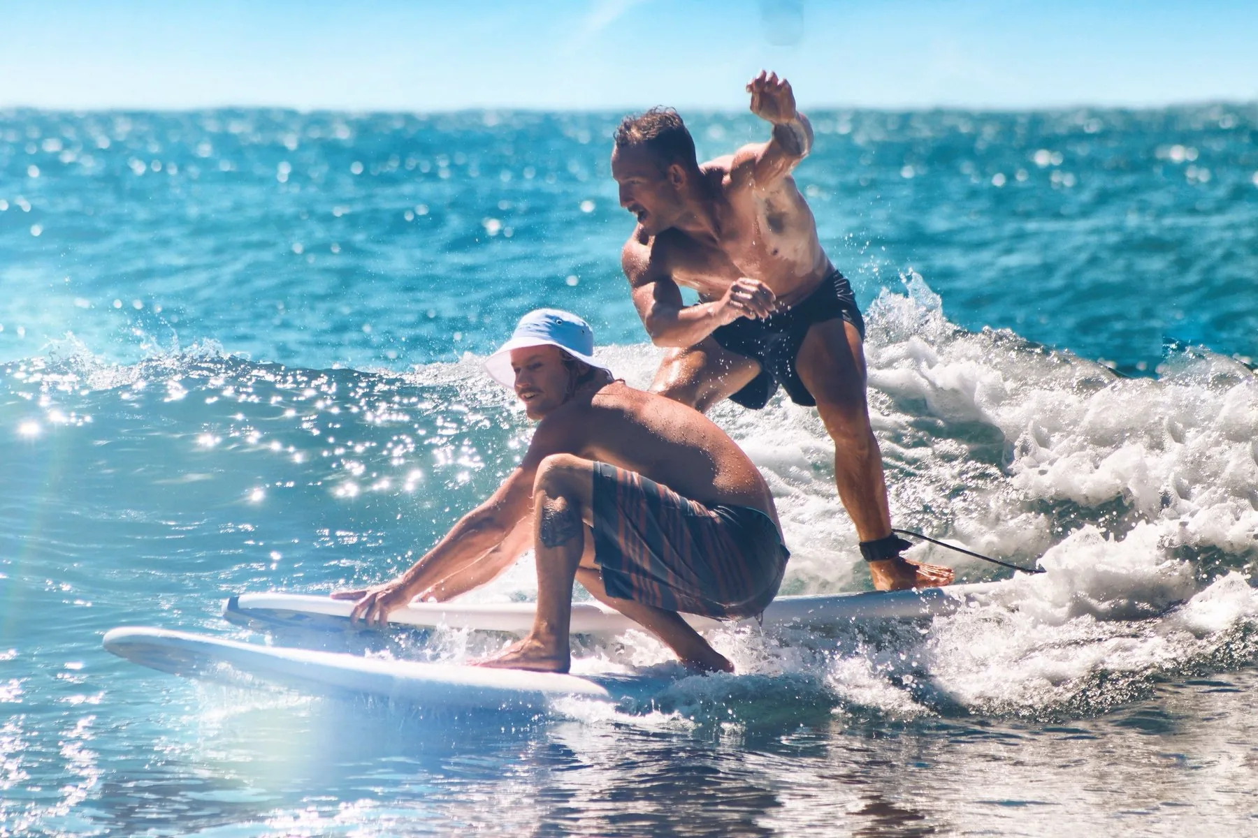Two men surfing a wave on a bright day